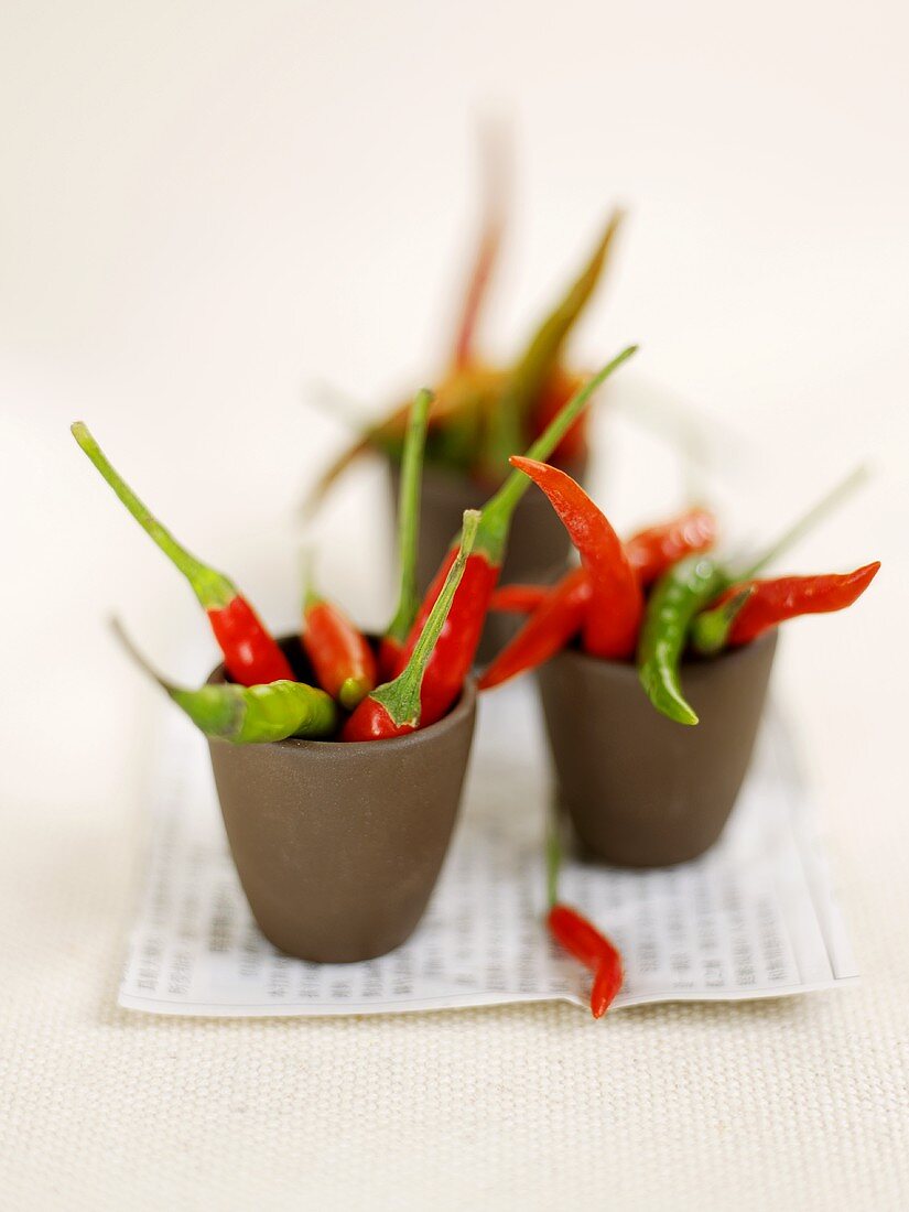 Several small, hot chili peppers in three small bowls