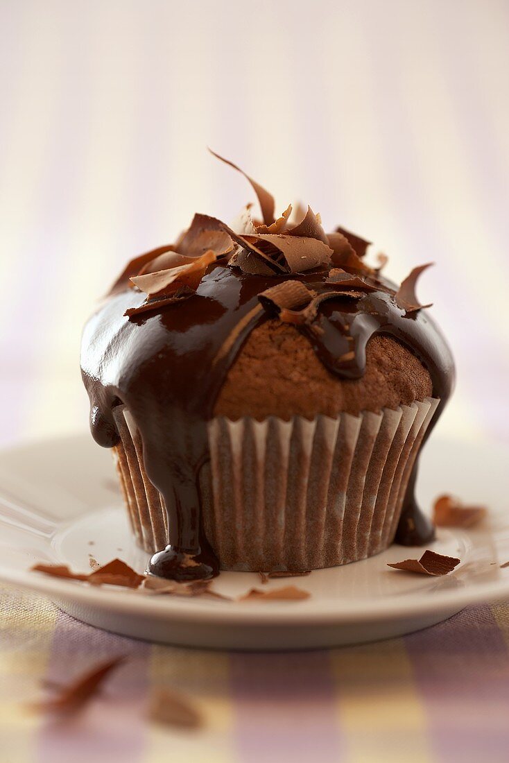 A chocolate muffin with chocolate sauce & chocolate curls