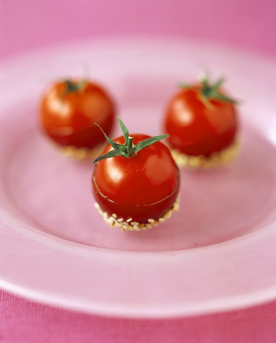 Three cherry tomatoes with sesame seeds sticking to them