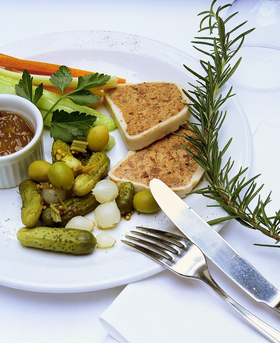 Two slices of meat terrine, gherkins and dip