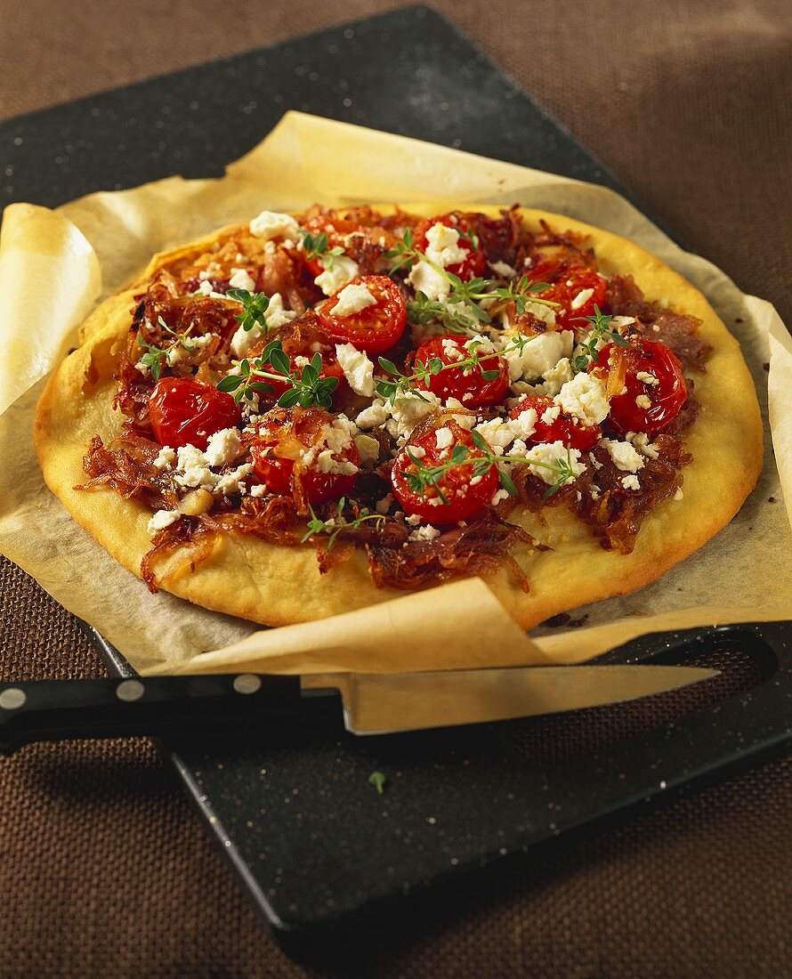 Pizza with onions, cherry tomatoes and feta on pizza tray