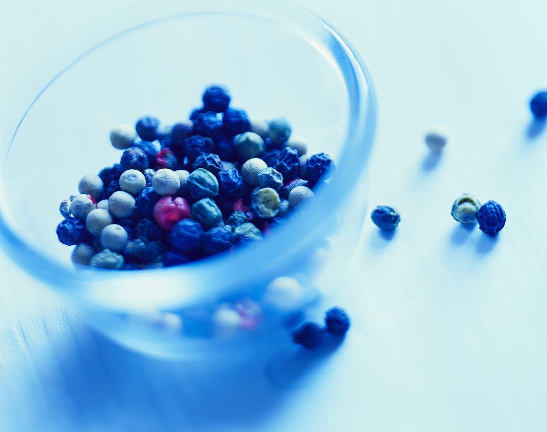 Peppercorns in and beside a glass bowl