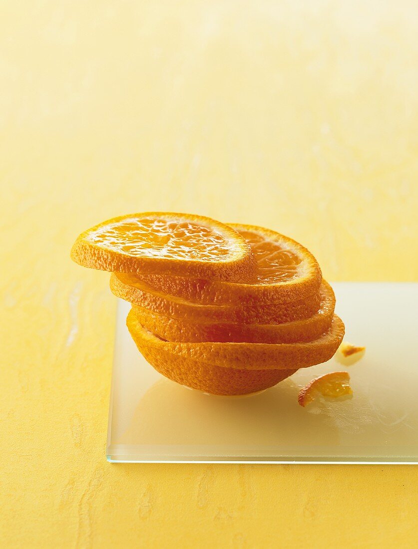 Slices of orange in a pile on a sheet of glass