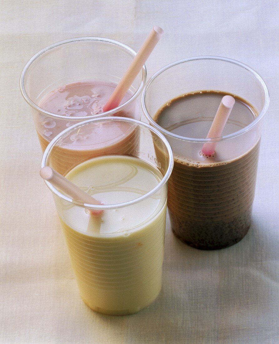 Strawberry, vanilla & chocolate milkshake in plastic beakers