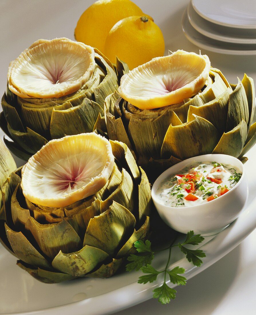 Three cooked artichokes with herb and pepper dip