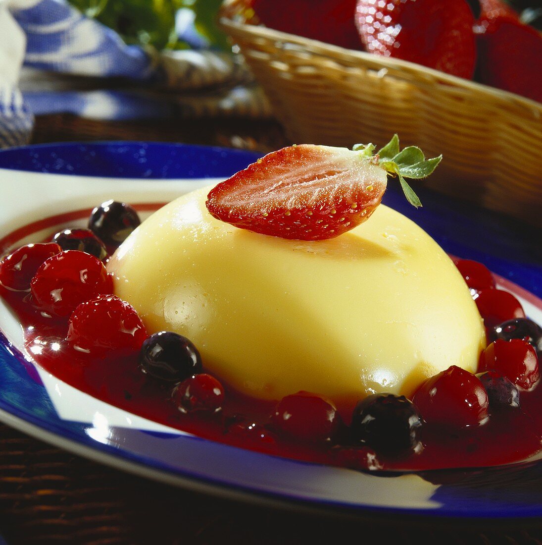 Turned-out vanilla blancmange surrounded by berry sauce