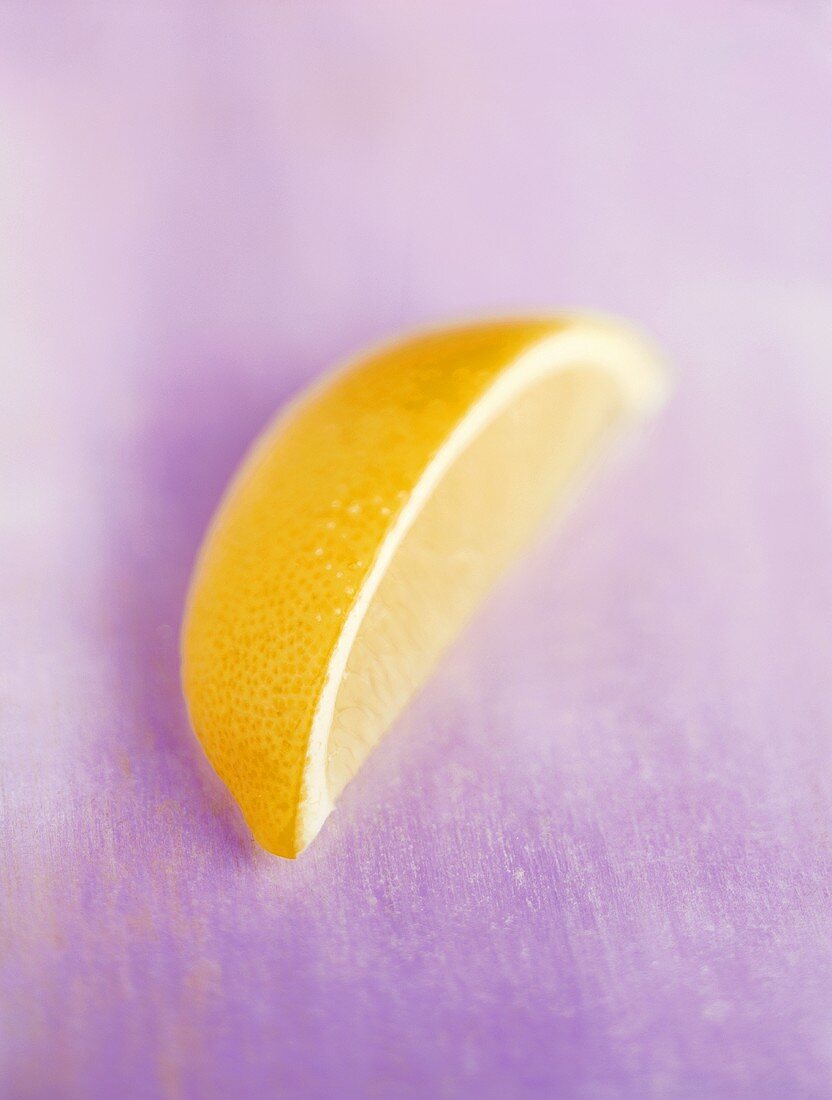 Wedge of lemon on violet background