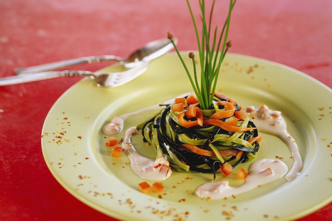 Bunte Nudeln mit Tomaten-Sahne-Sauce auf grünem Teller