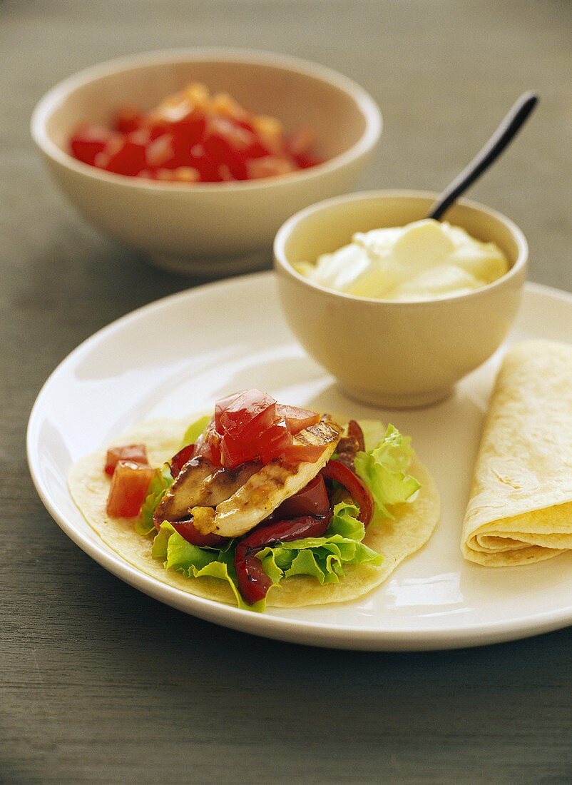 Chicken with tomatoes, green salad and peppers on tortillas