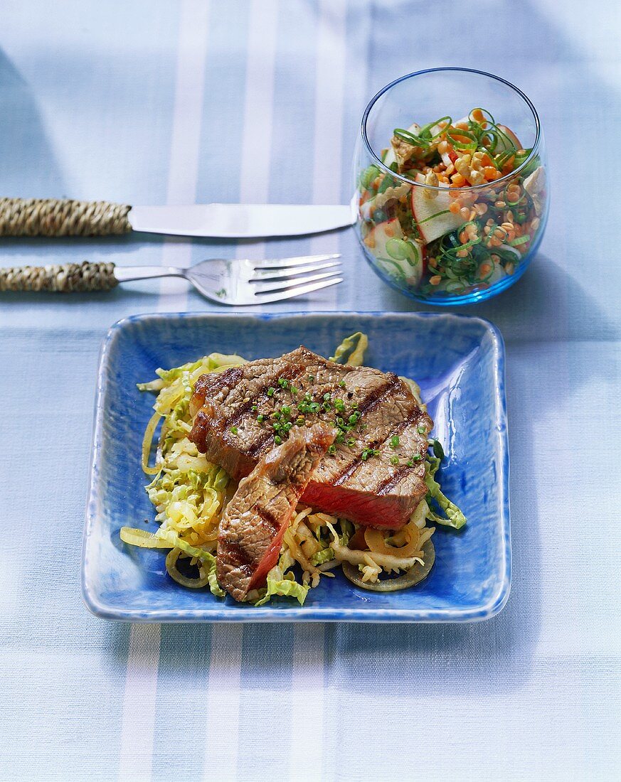 Grilled rump steak on salad leaves with fruit & leek salad