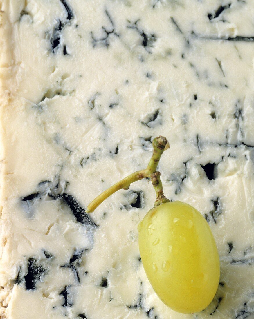 A grape lying on gorgonzola (filling the picture)