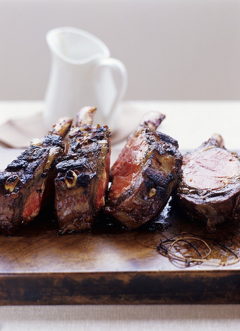 Vier gegrillte Ribeye-Steaks auf einem Holzbrett