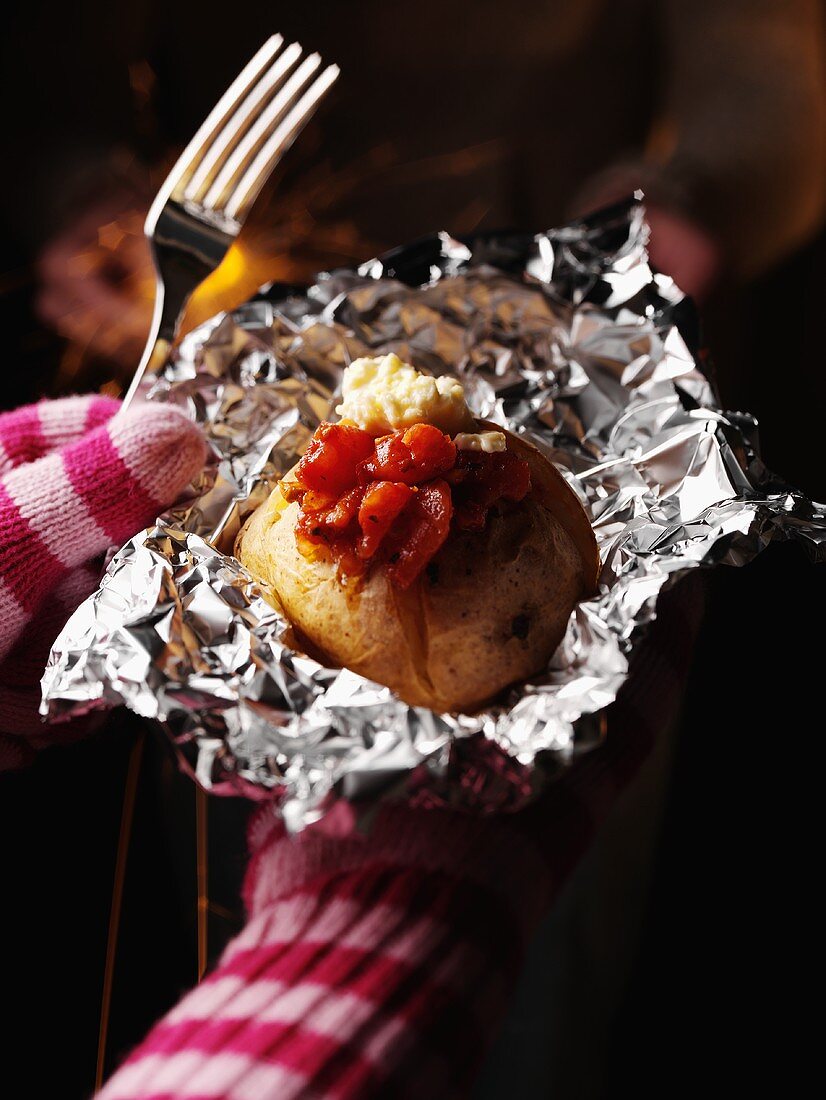 Baked potato in a gloved hand