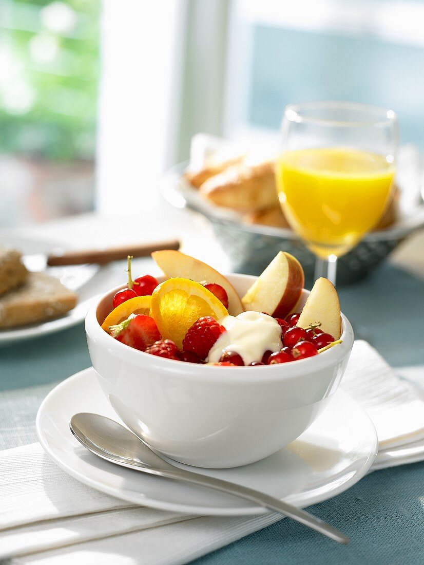 Frühstückstisch mit einer Schale Obst und Orangensaft