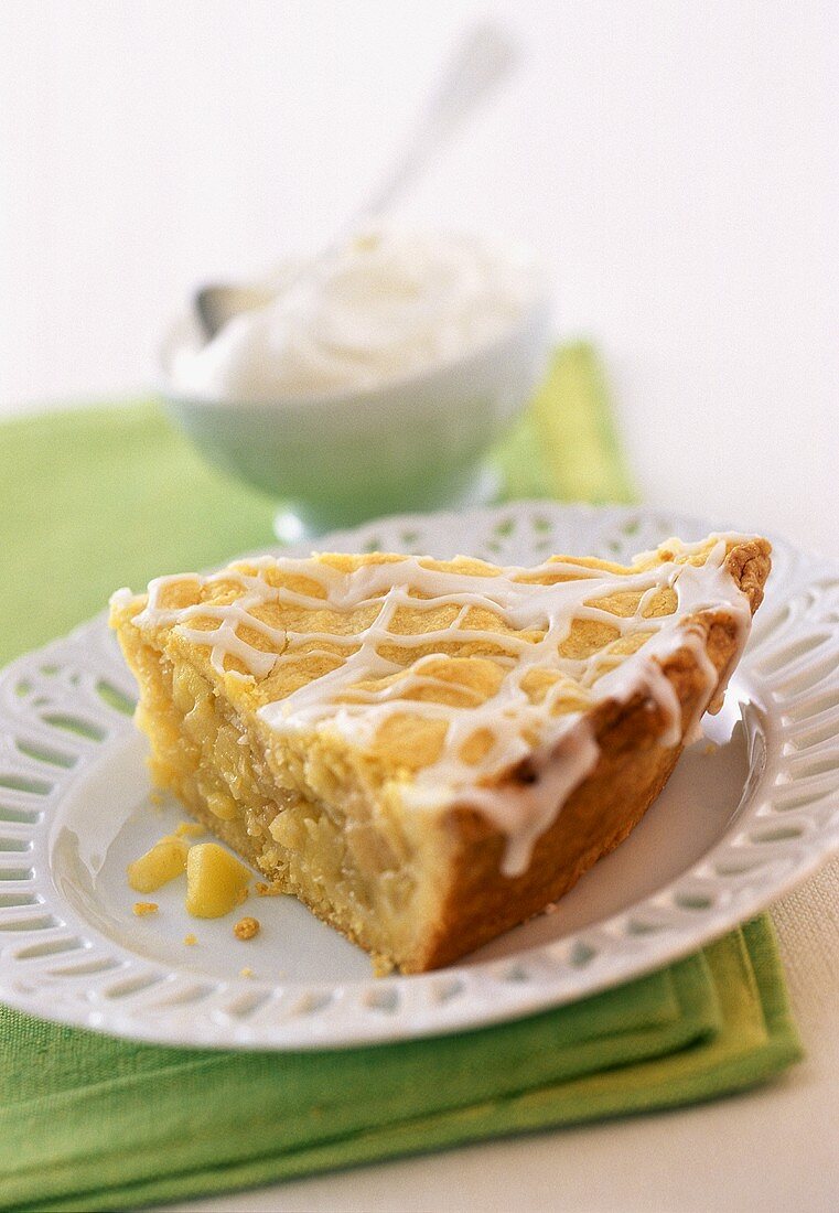 A piece of apple cake with a bowl of whipped cream