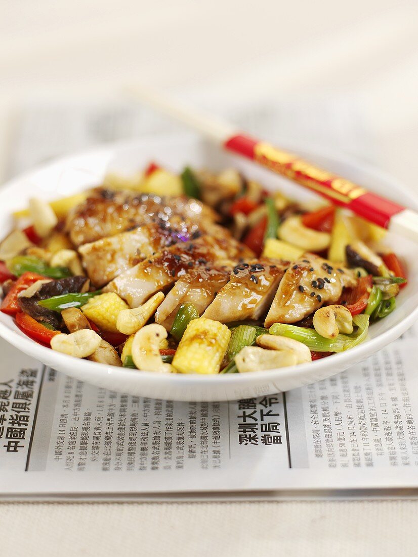 Chicken with sesame and vegetables on a newspaper
