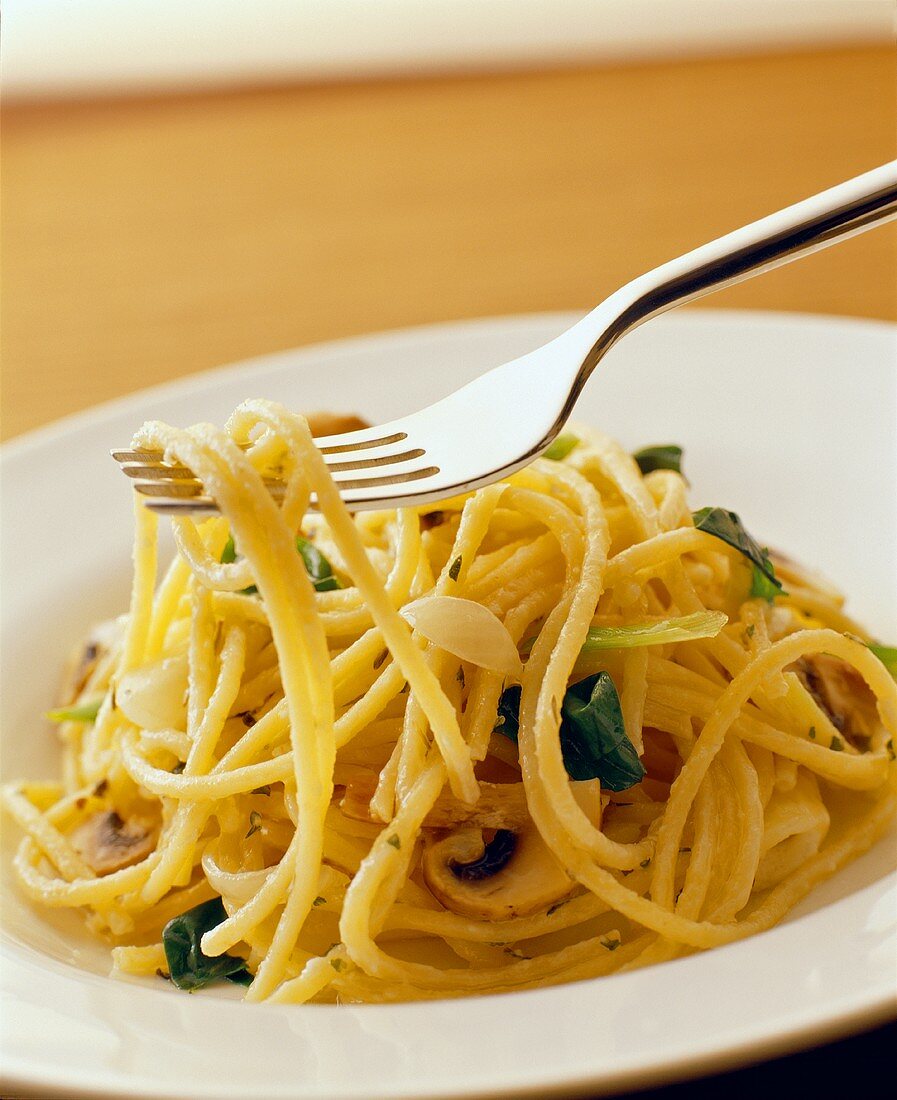 Spaghetti mit Basilikum und Pilzen auf einer Gabel