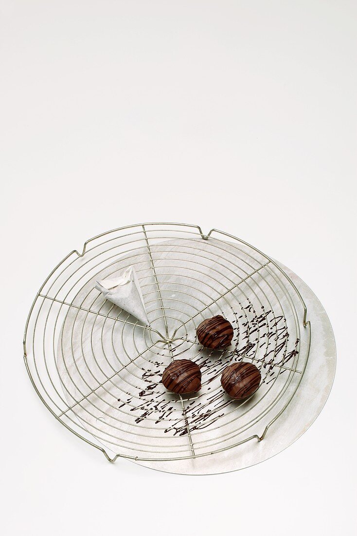 Drei mit Schokolade verzierte Pralinen auf Kuchengitter