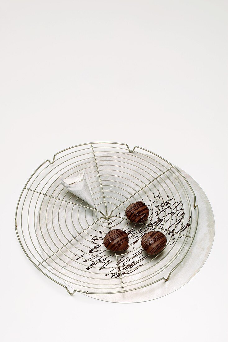 Three decorated chocolates on cake rack