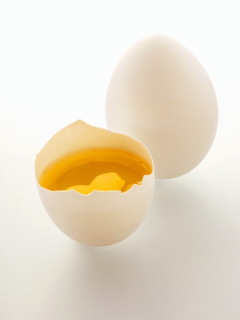A Cracked Open Egg Shell with Yolk and Whole Egg