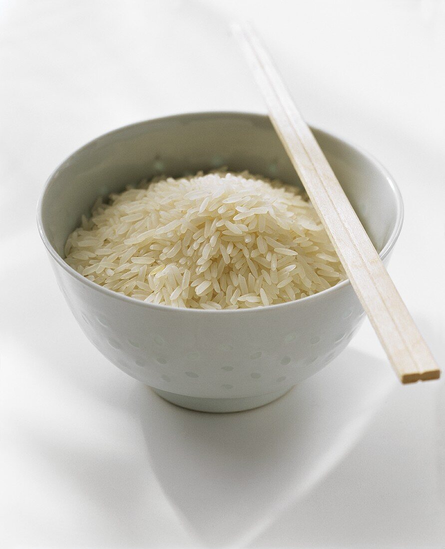 A Bowl of Uncooked White Rice with Chopsticks
