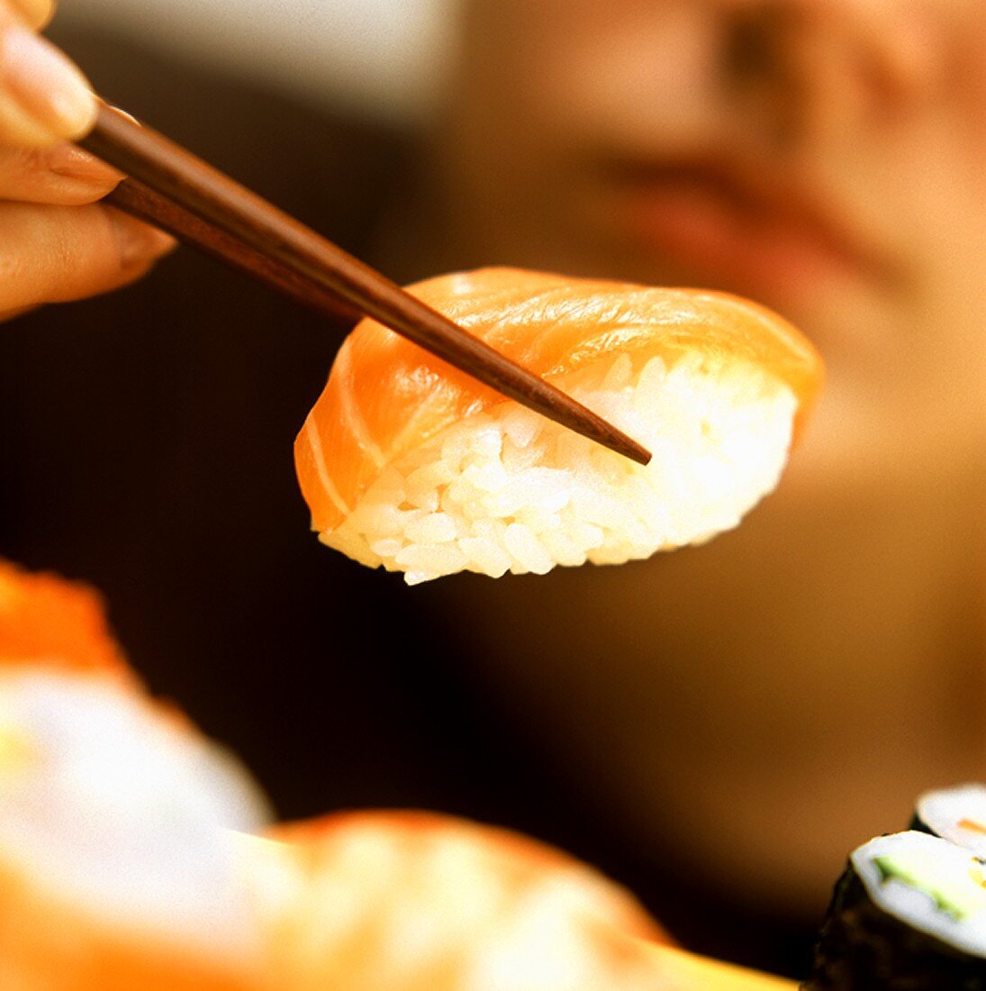 A Piece of Sushi Being Held on Chopsticks