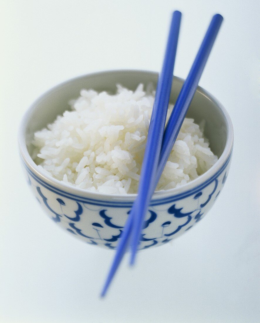 Cooked rice in Asian bowl with chopsticks