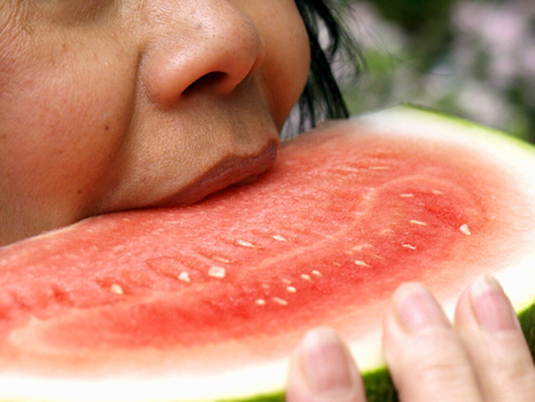 Frau beisst in Wassermelonenspalte