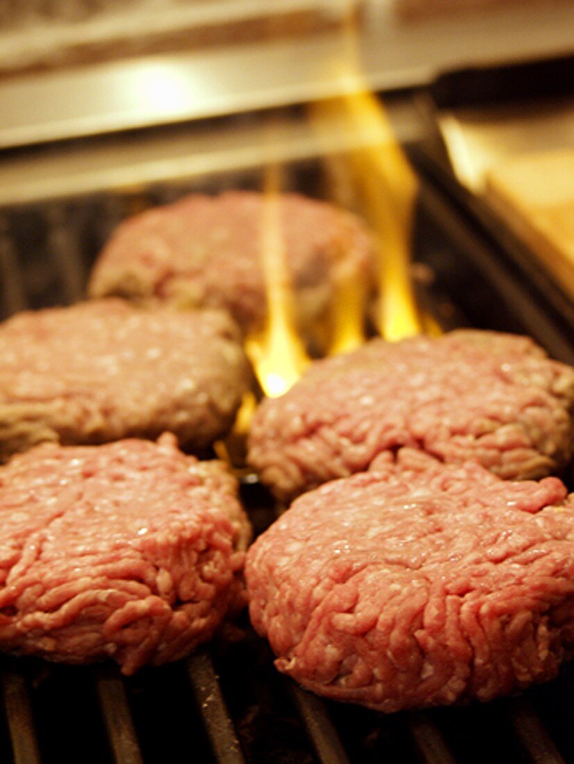 Several Hamburger Patties on the Grill with Flames