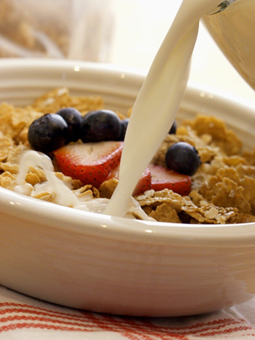 Milch in Schale mit Cornflakes gießen