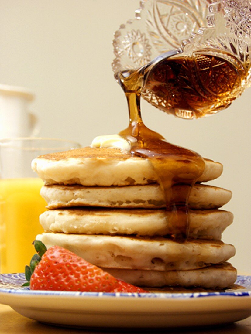 Pouring Syrup Over a Stack of Pancakes