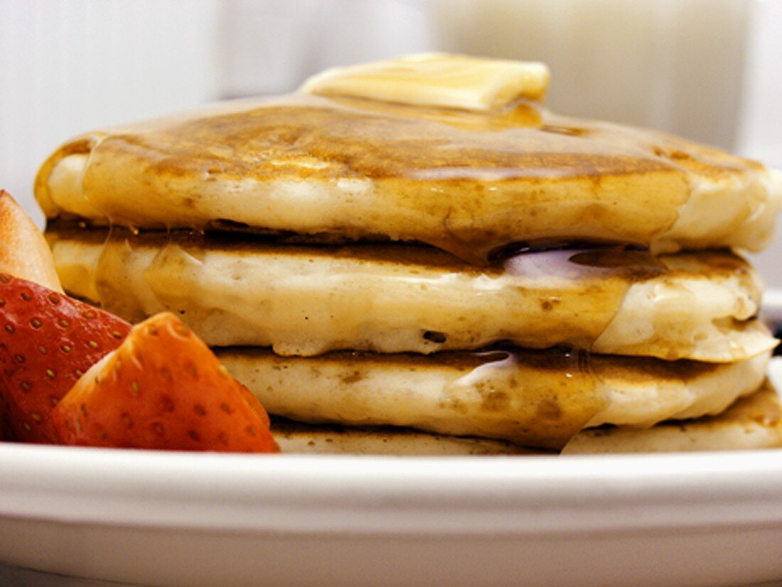 Pancakes mit Ahornsirup, Butter und Erdbeeren