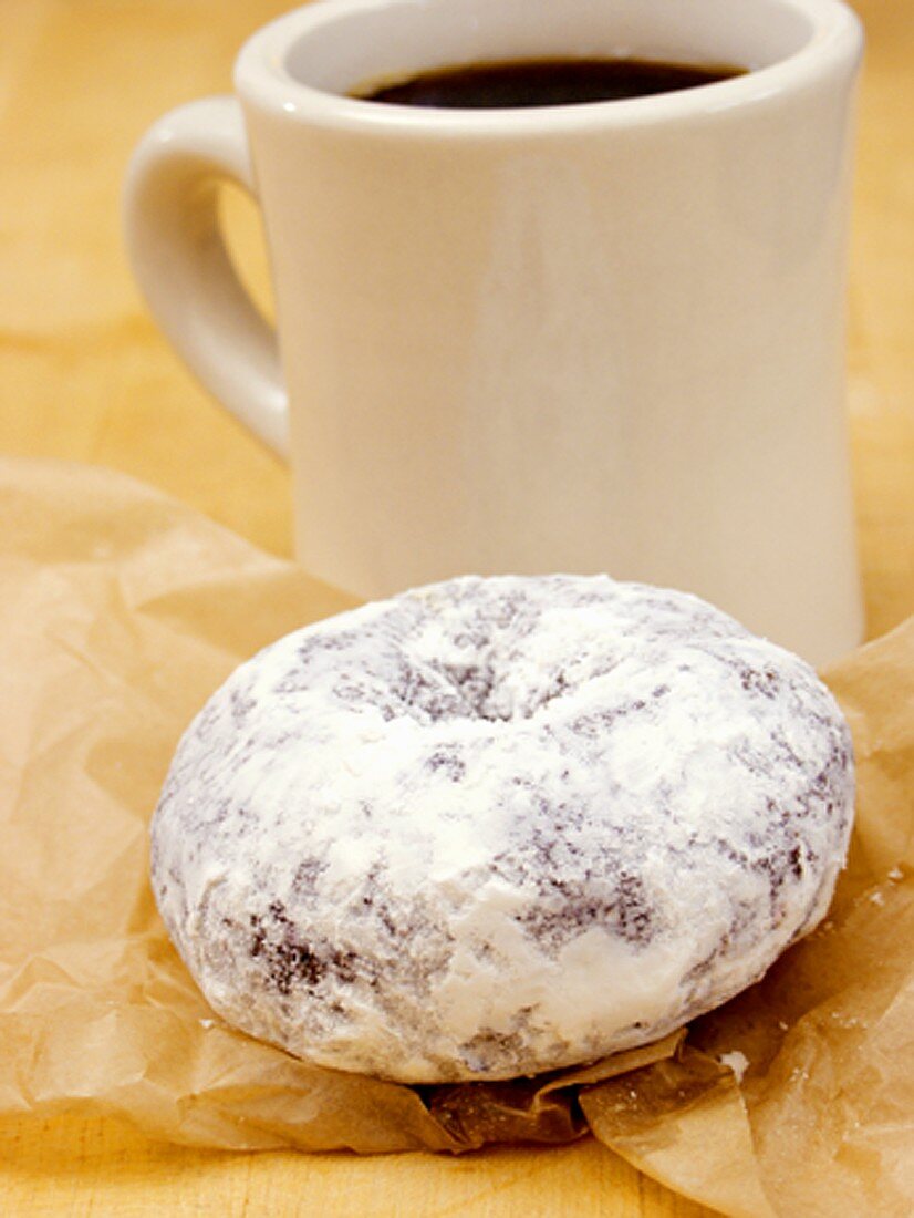 A Powdered Donut with Mug of Coffee