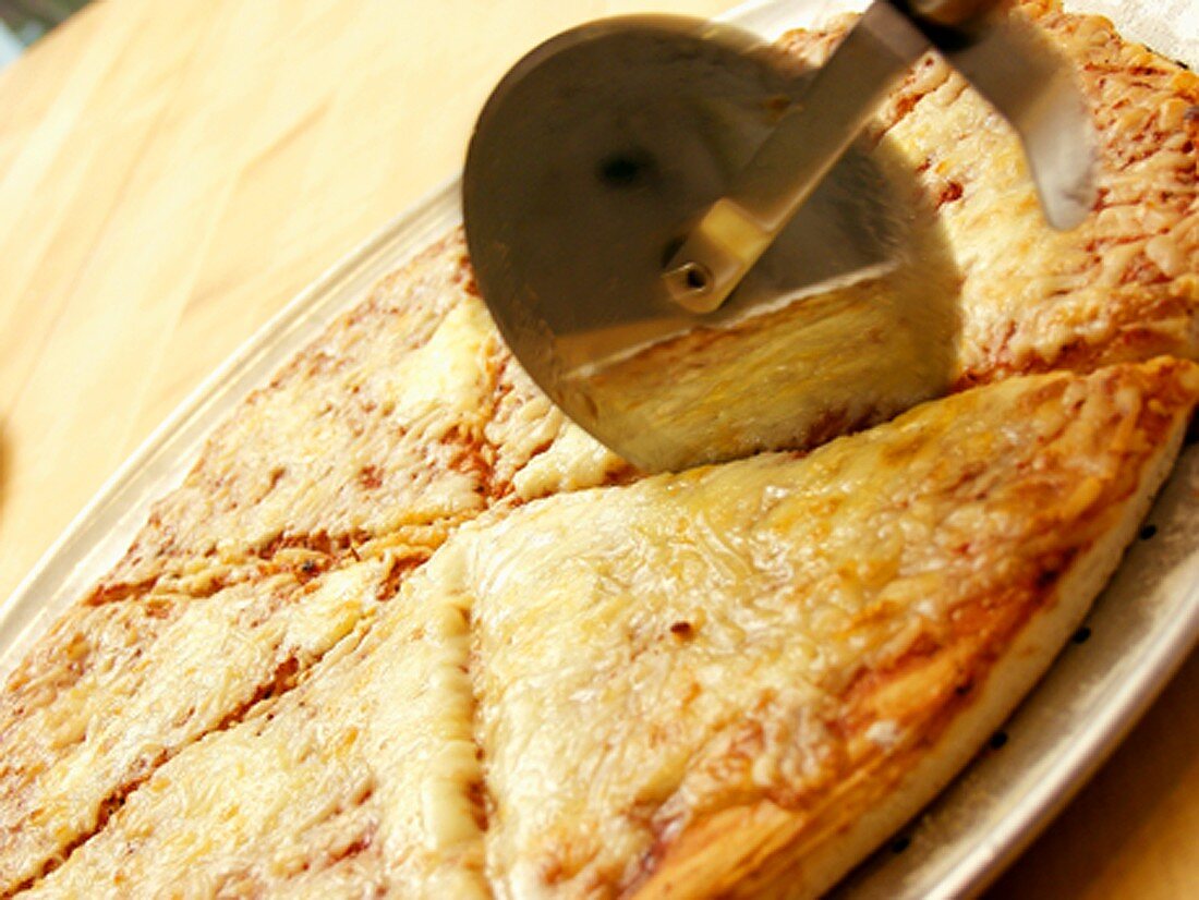 A Pizza Cutter Slicing Through a Cheese Pizza
