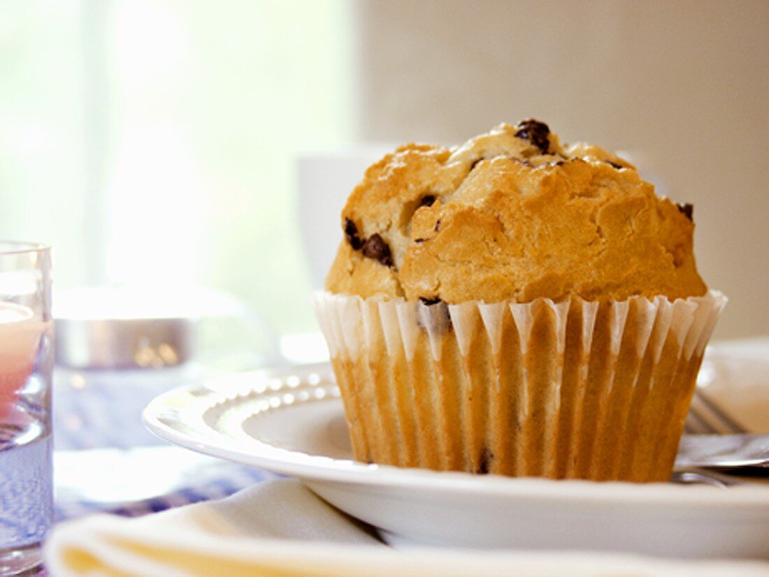 Chocolate Chip Muffin auf Teller vor Kaffeetasse