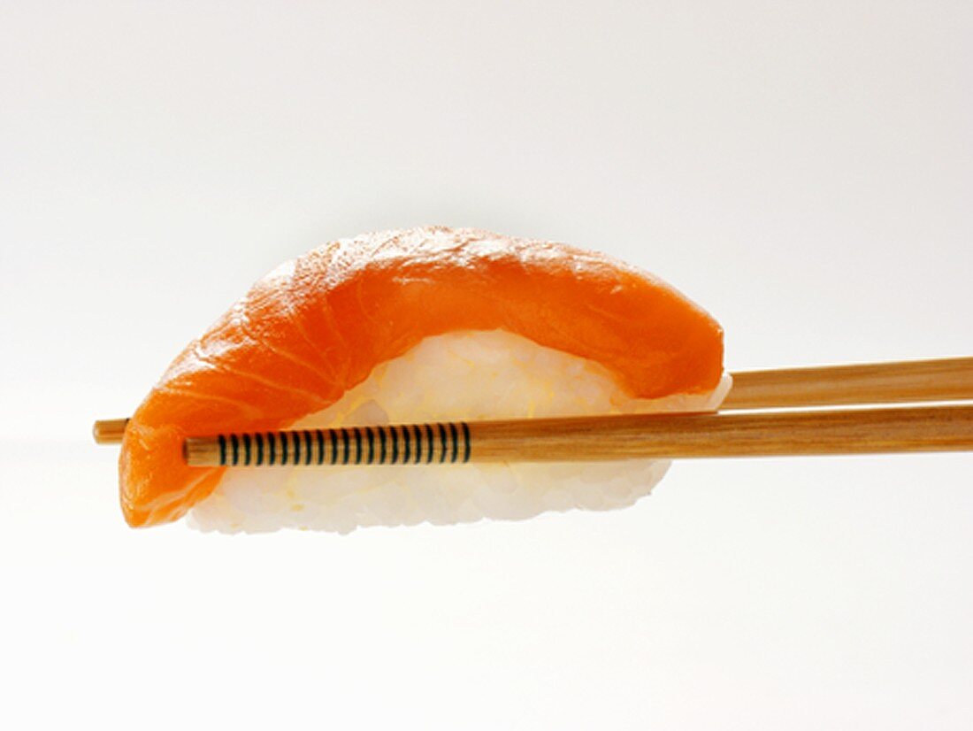 Stäbchen halten Nigiri-Sushi mit Lachs
