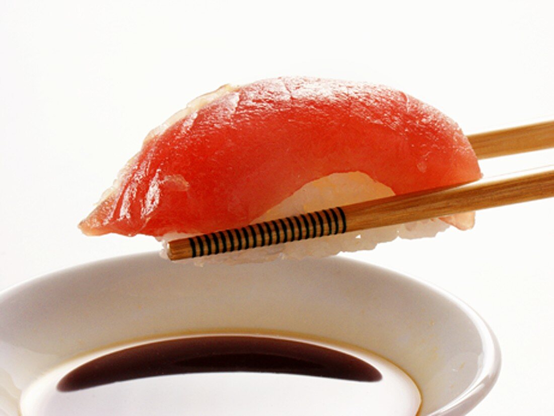 Stäbchen halten Maguro Sushi über Sojasauce