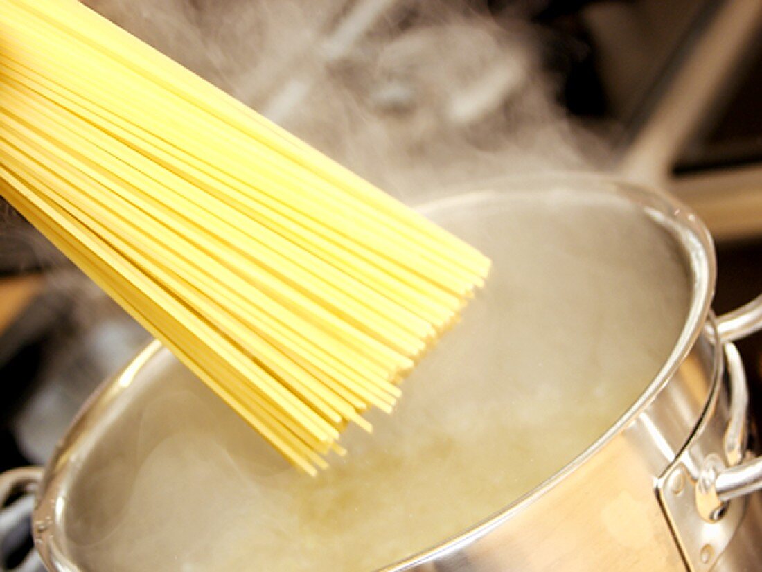 Spaghetti in Topf mit kochendem Wasser geben