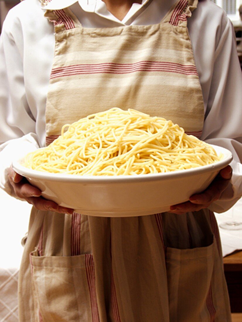 Frau hält grosse Schüssel Spaghetti