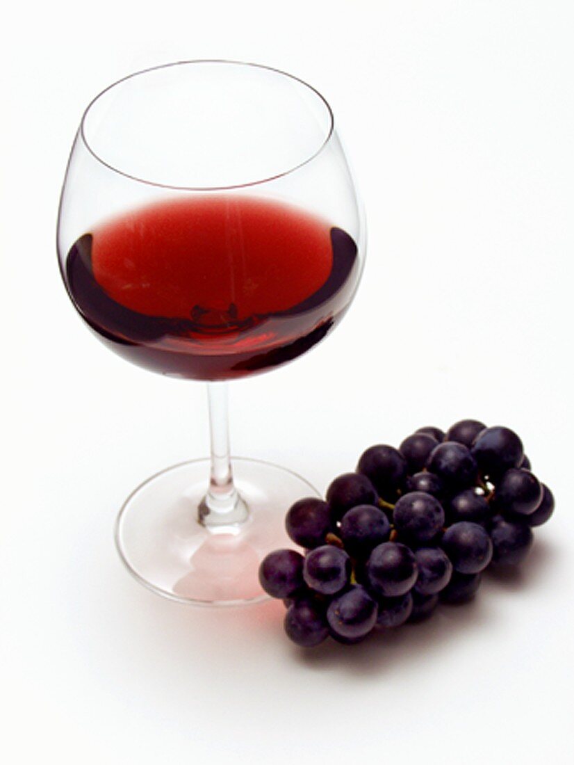 Glas Rotwein und blaue Trauben