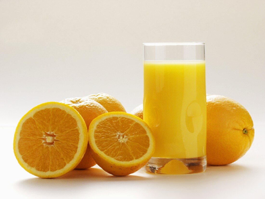 Glas Orangensaft und frische Orangen