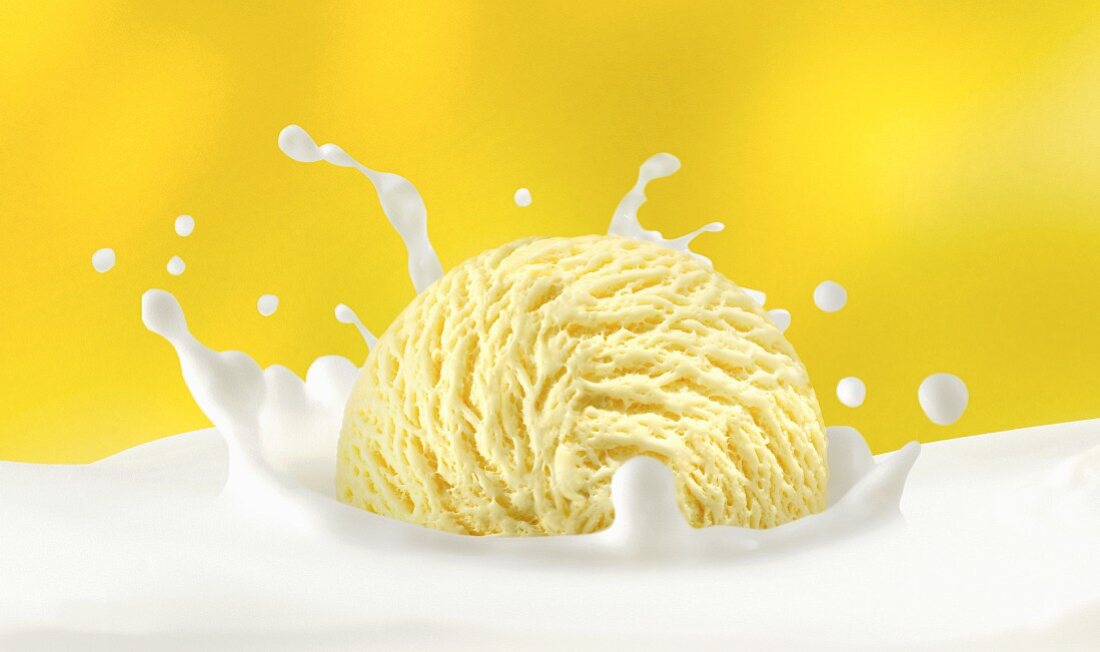 A scoop of vanilla ice cream falling into milk