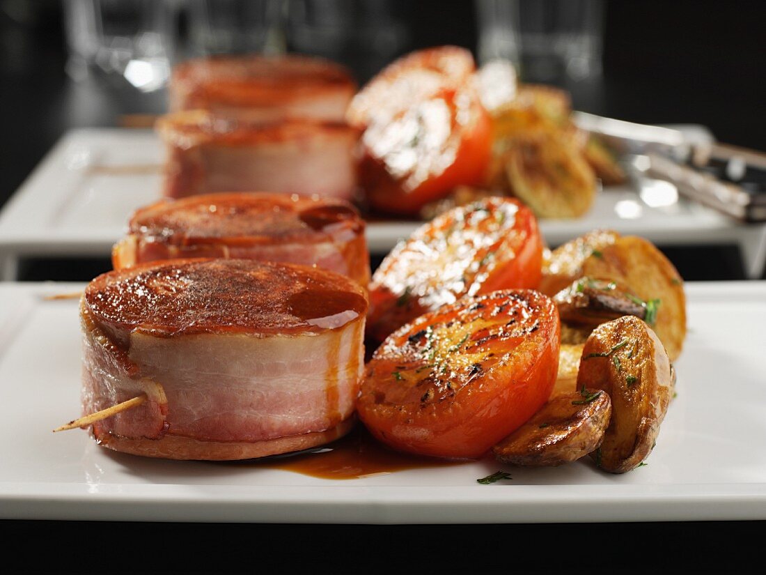 Slice of sausage wrapped in bacon, tomatoes and potatoes