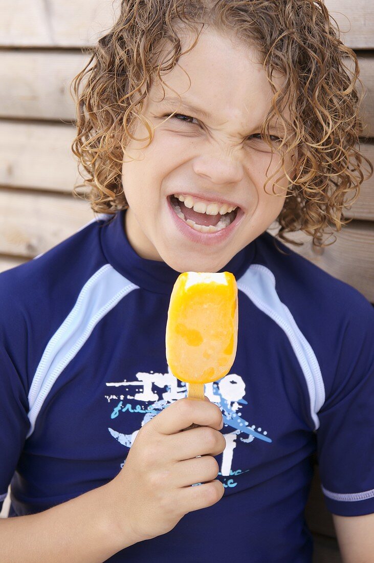 Boy with wet hair eating an ice lolly