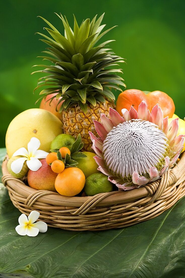 Basket of tropical fruit, plumeria and protea