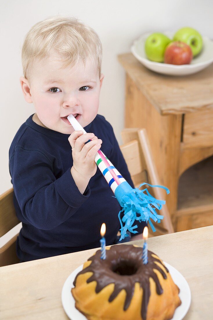 Small boy with birthday cake (gugelhupf) and horn