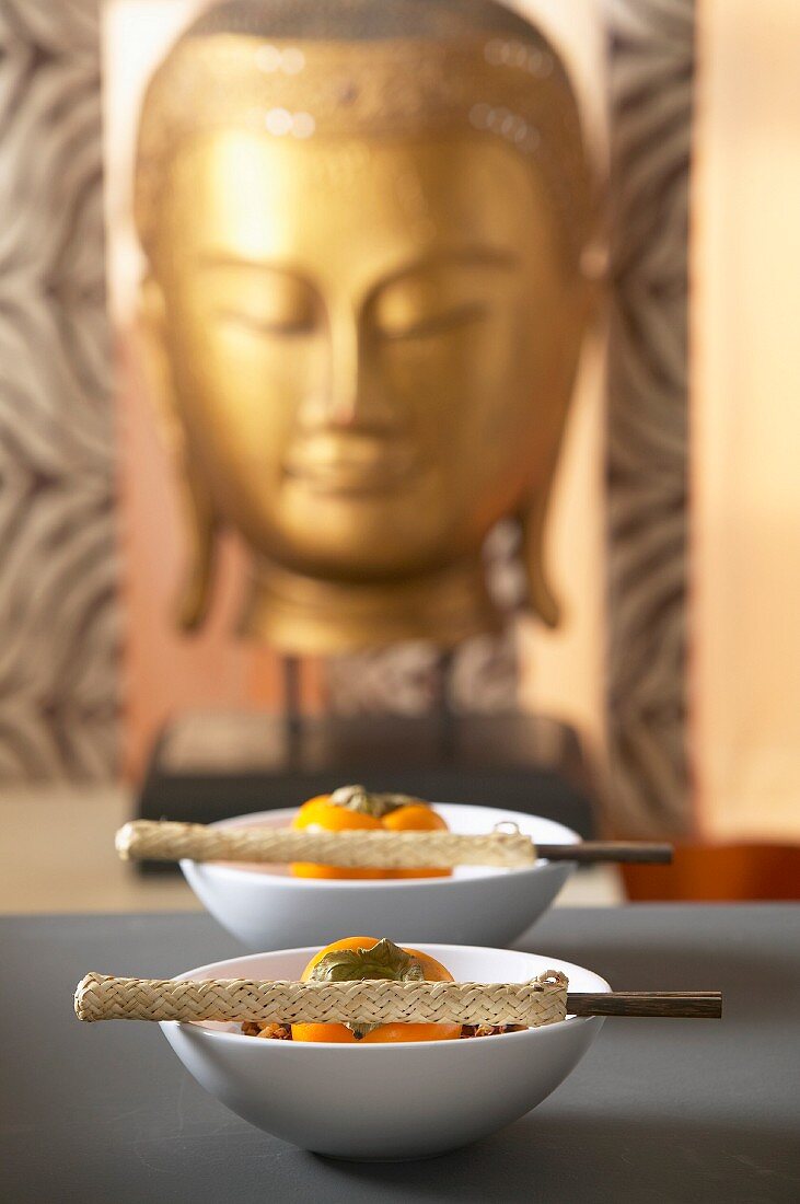 Persimmons in small bowls with chopsticks