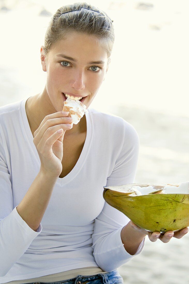 Junge Frau isst Kokosnuss