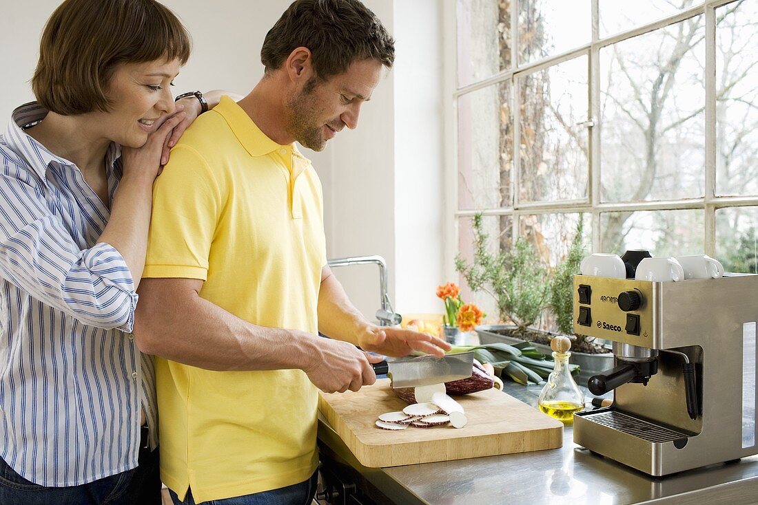 Man slicing vegetables, woman looking over his shoulder