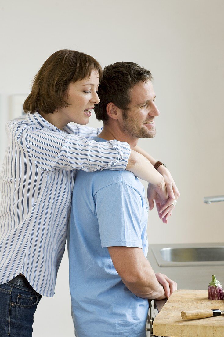 Woman embracing man from behind in a kitchen